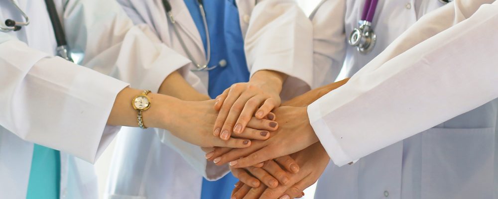 Doctors and nurses in a medical team stacking hands.